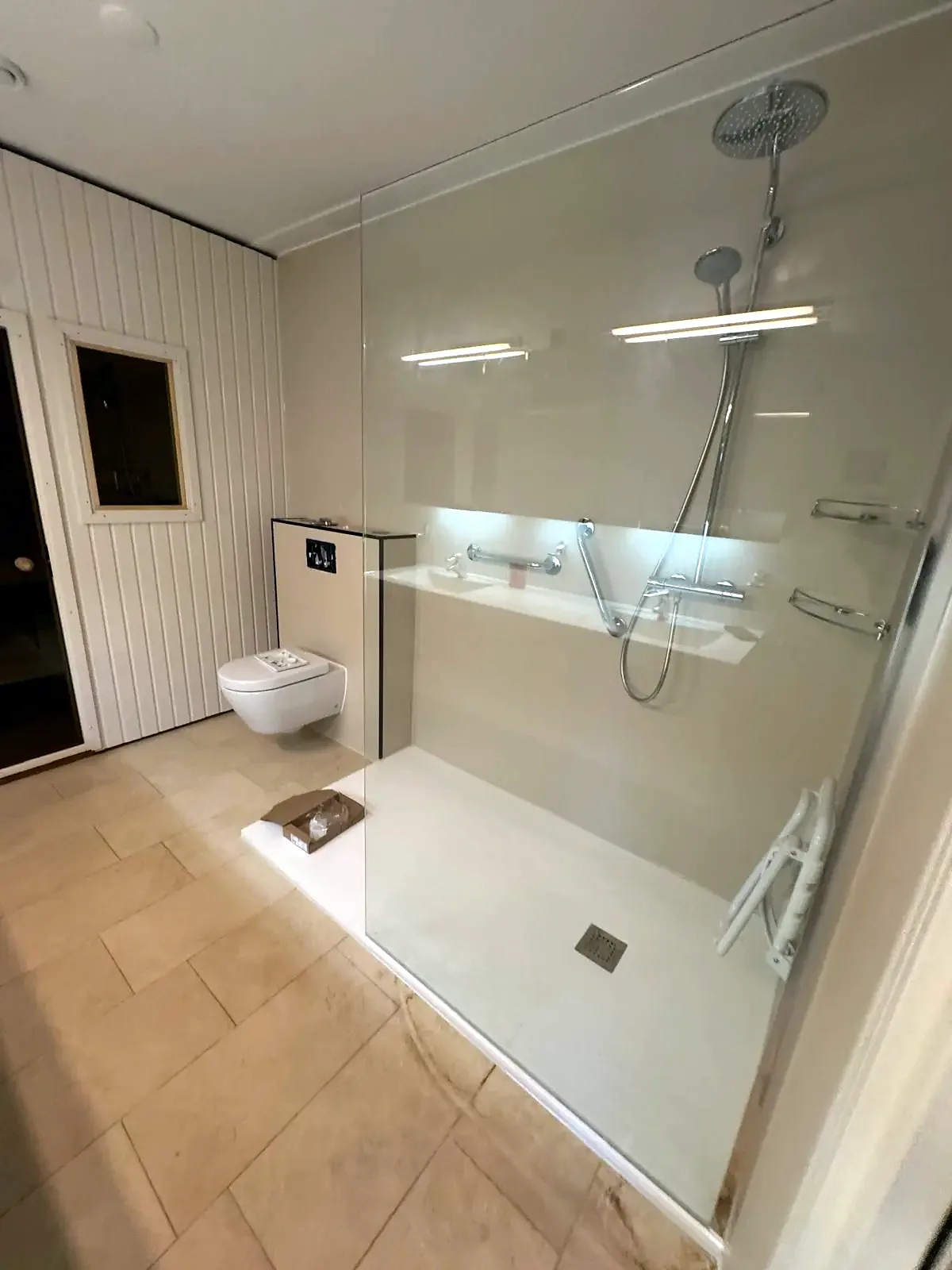 Brede inloopdouche met marmerlook wand, glazen wand en verlichte nis