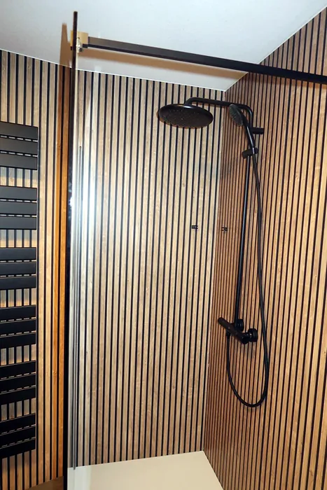 Zwarte regendouche tegen houtlook lamellenwand